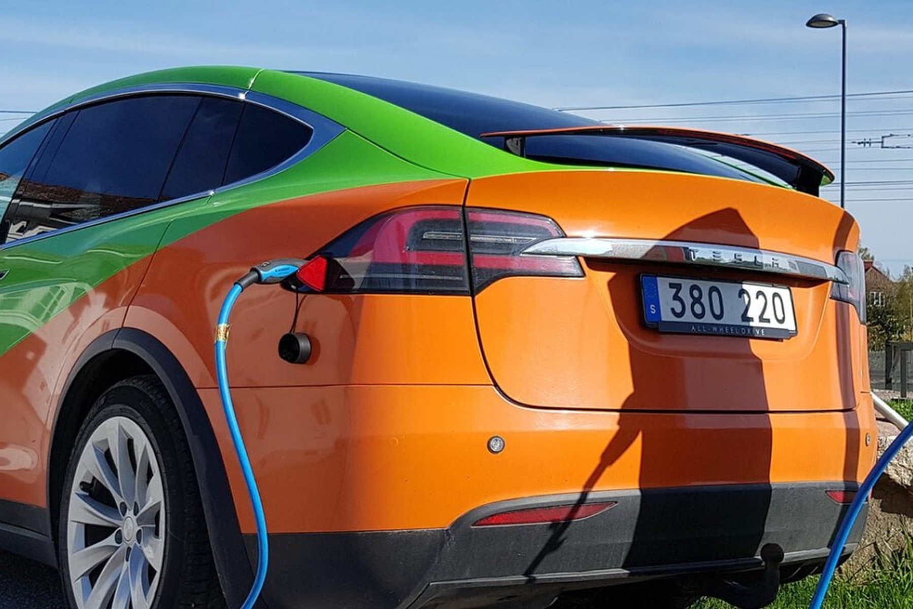Porträtt på Jimmy Wilhelmsson på Elektrikern med en elbil i bakgrunden